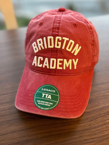 Red cap with 'Bridgton Academy' text on a wooden surface