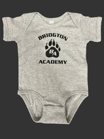 A heather gray baby bodysuit with a black printed graphic on the chest that reads 'BRIDGTON ACADEMY' around a paw print with 'BA' inside, laid flat on a dark gray surface.